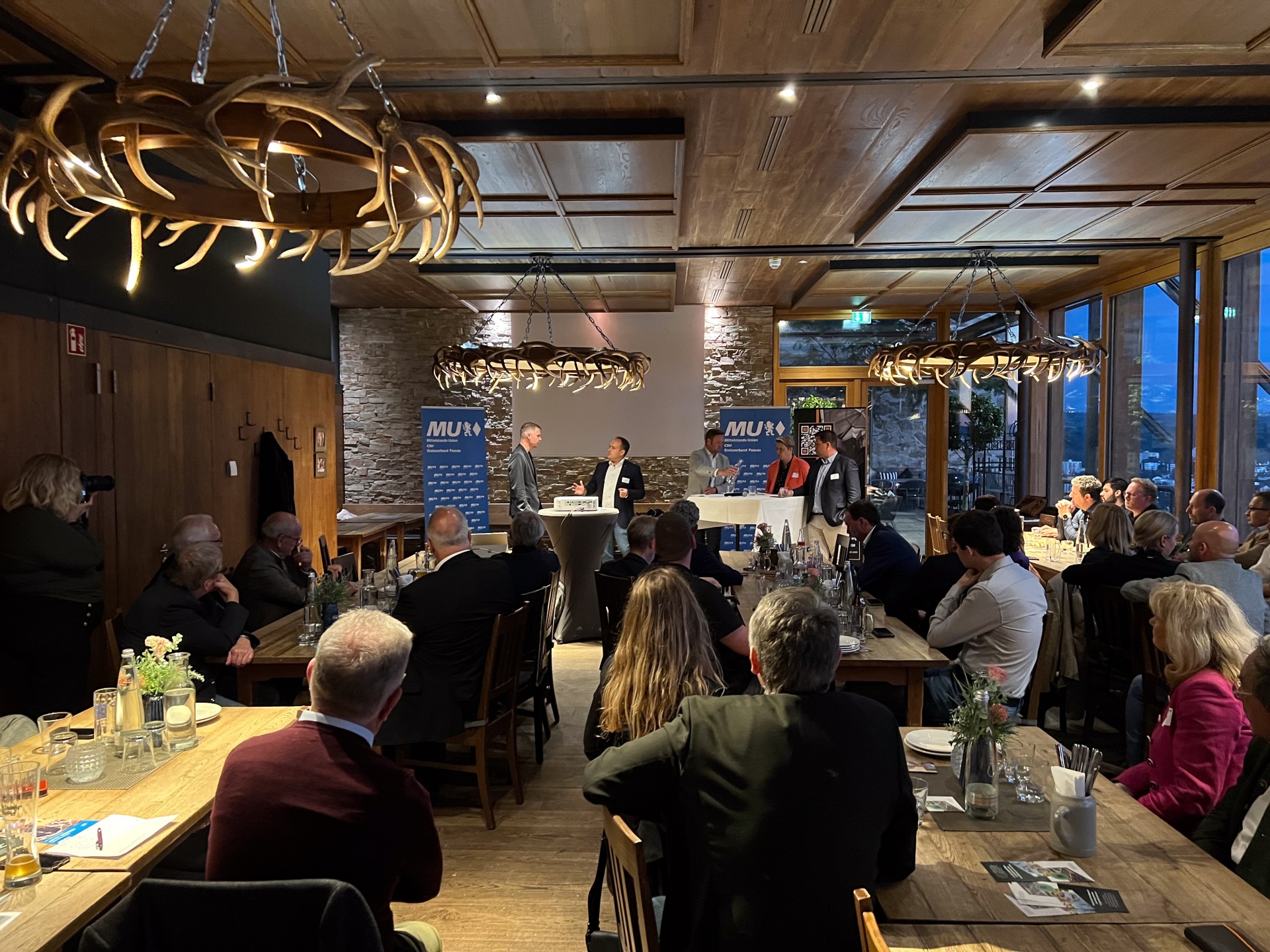 Gäste verfolgen einen Vortrag bei einer Abendveranstaltung im rustikal eingerichteten Restaurant „Das Oberhaus“ in Passau.